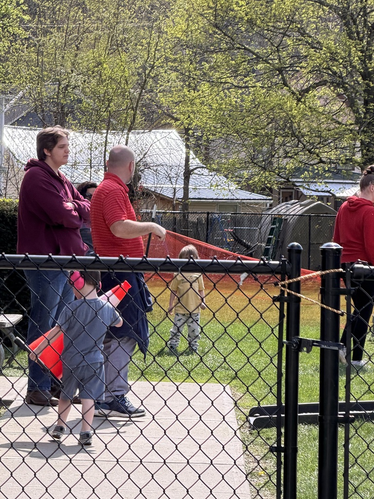 A group of students and staff outside behind a fence.