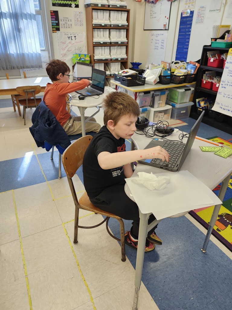 Two students on computers at their desks.