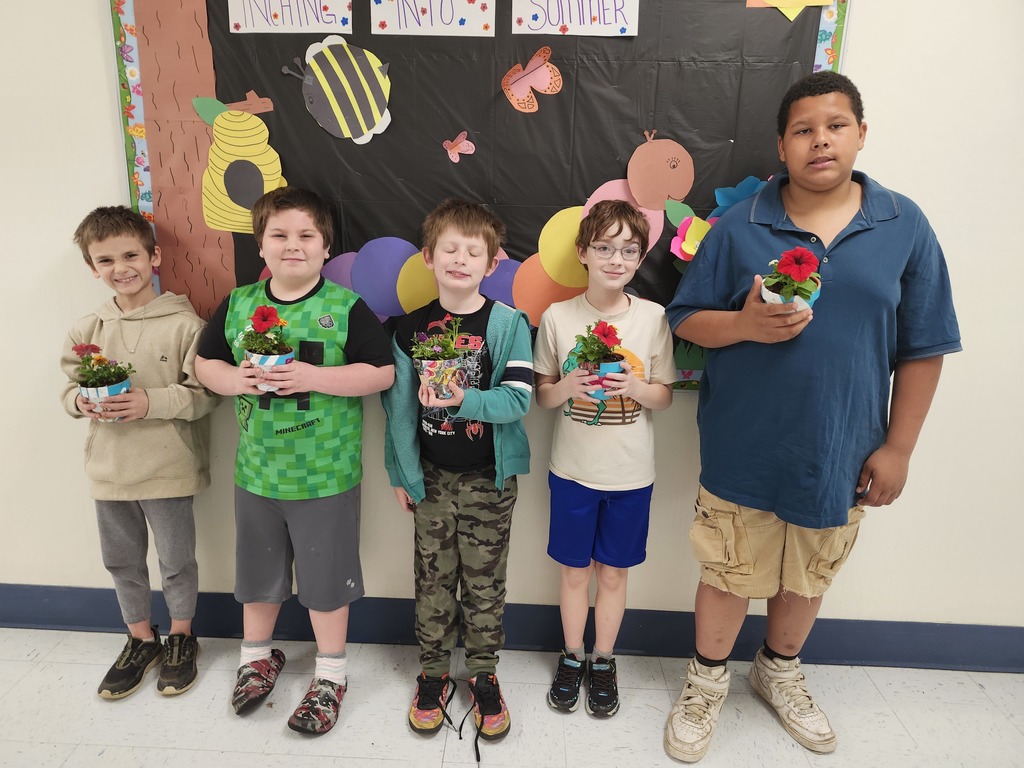 Five students smiling holding Mother's Day gifts.