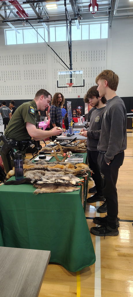 Business owners explaining fur items at a table to students