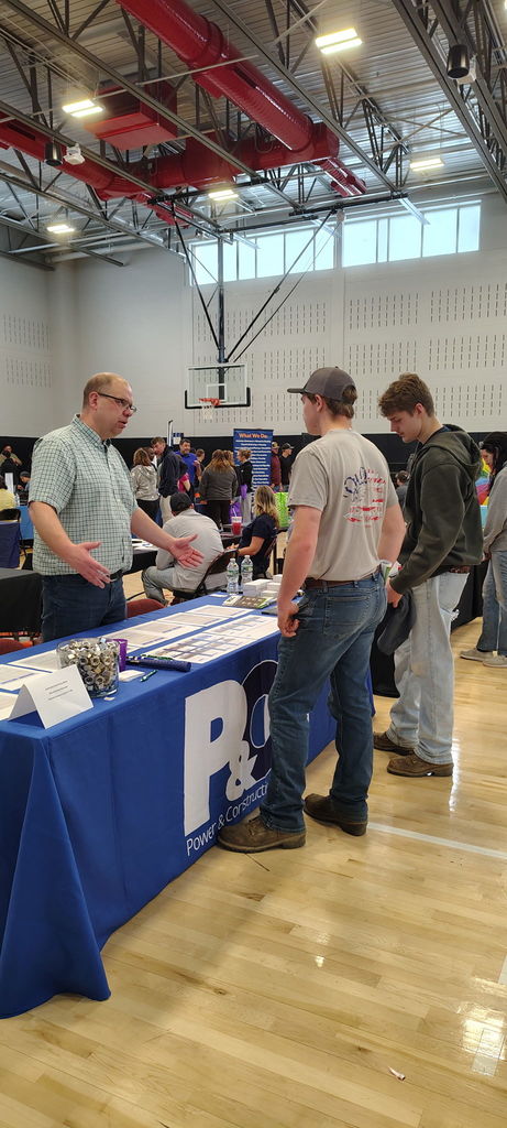 Two students talking to a business owner at a table