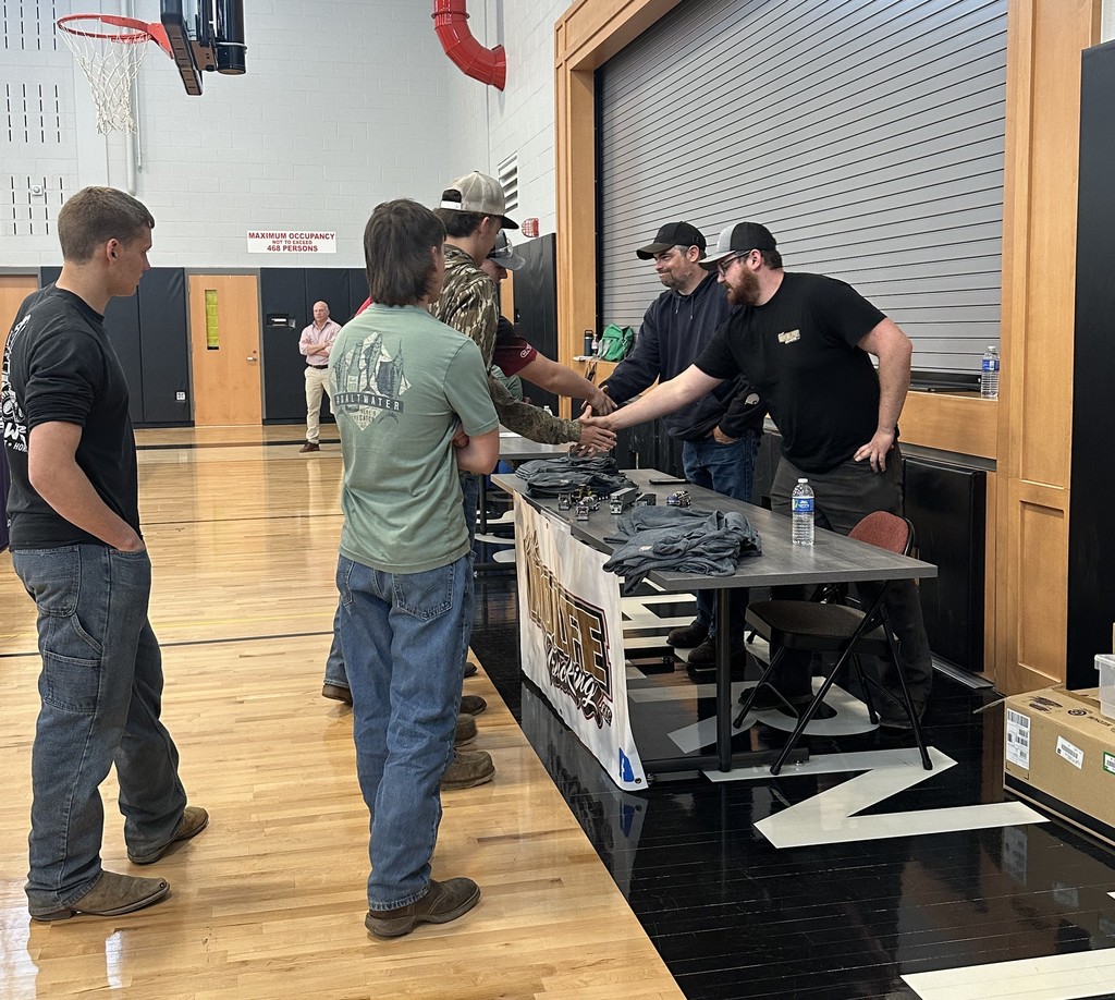 Business owners and students shaking hands at a table