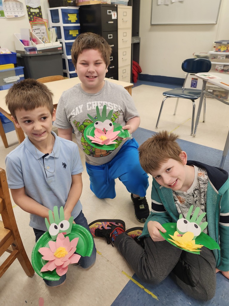 Three students smiling with thier frog on a lily pad project.