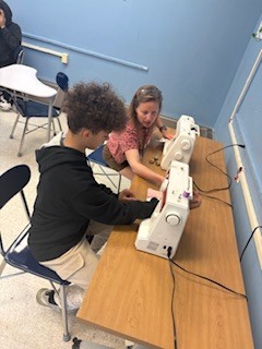 Teacher helping student at sewing machine