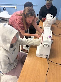 Teacher helping student at sewing machine