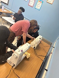 Teacher helping student at sewing machine