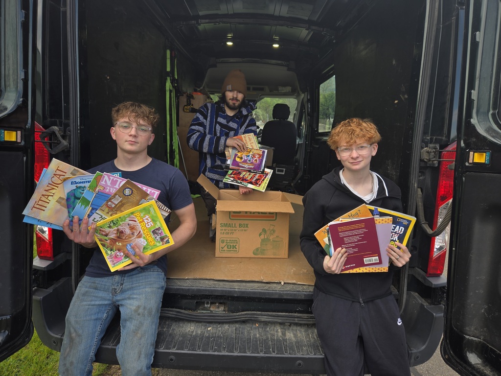 Three students holding some of the books they donated.