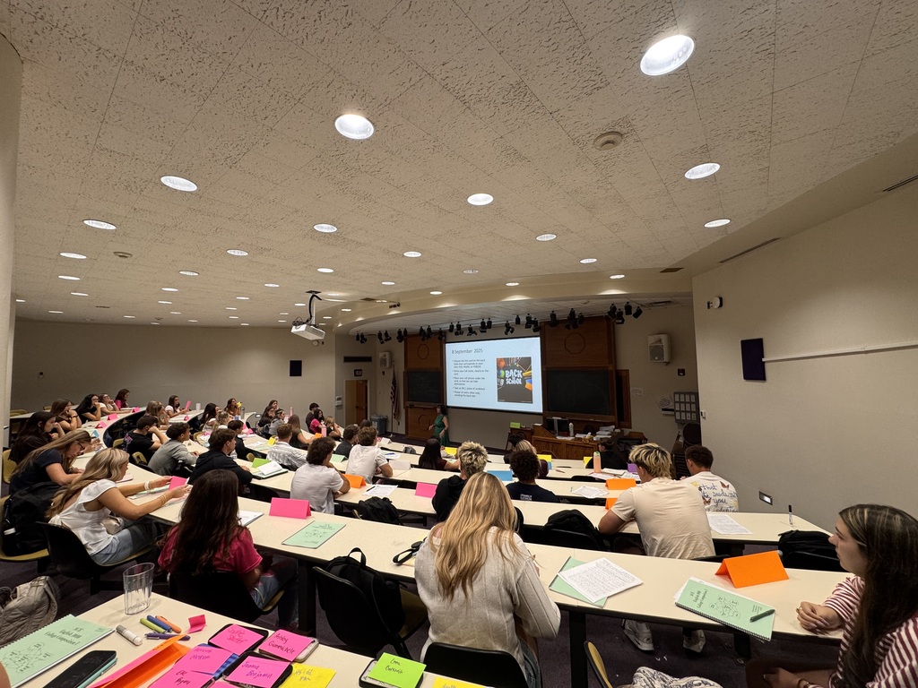 Students sitting at tables looking at the front of the class