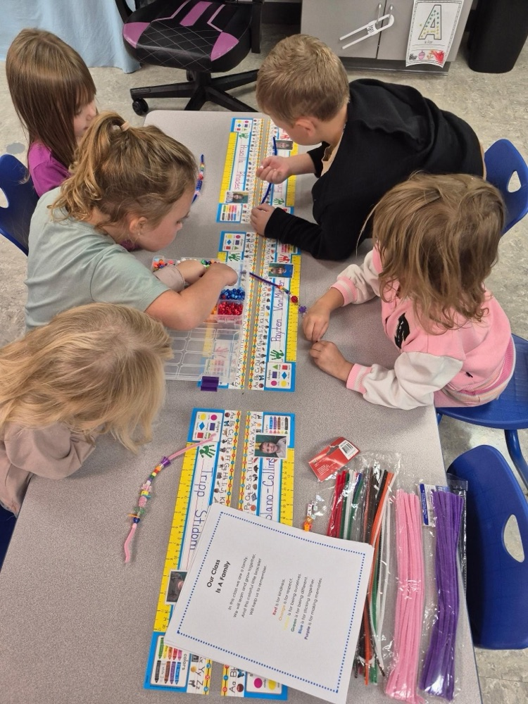 Kids sitting at a table using beads and pipe cleaners to make friendship bracelets 