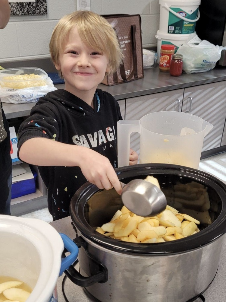 student stirring apples in a crockpot
