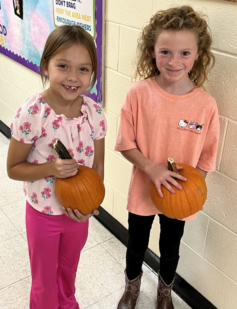 two girls holding pumpkins
