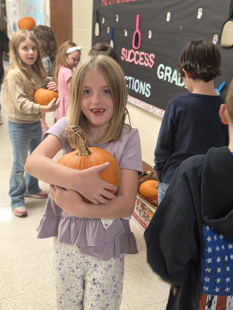 one girl holding a pumpkin. other kids in the background
