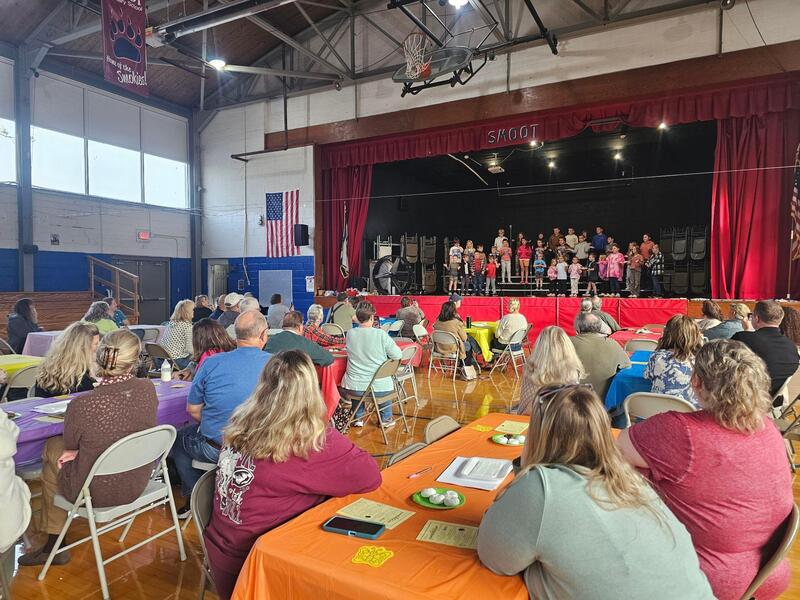 students singing to families at tables during grandparents day celebration