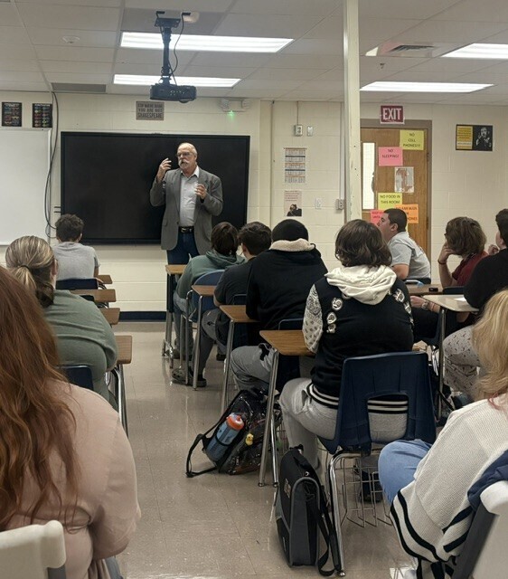 man speaking to students in desks