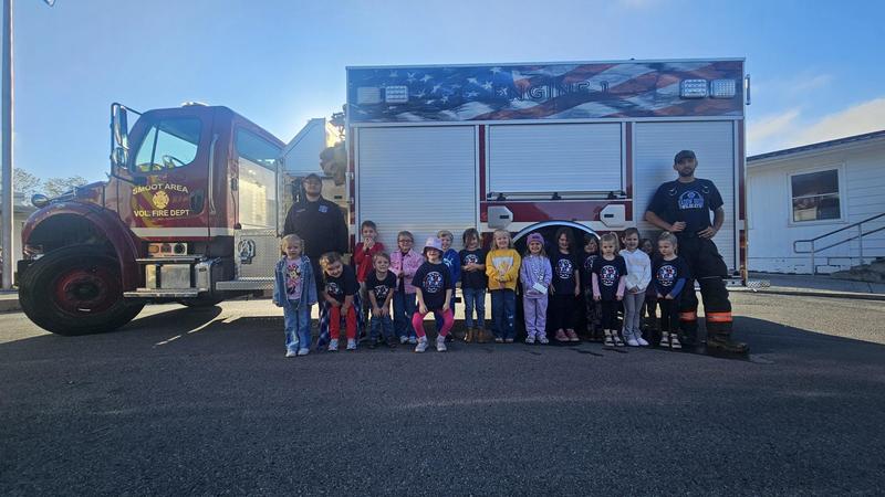 group of firefighters and prek age children in front of full fire engine