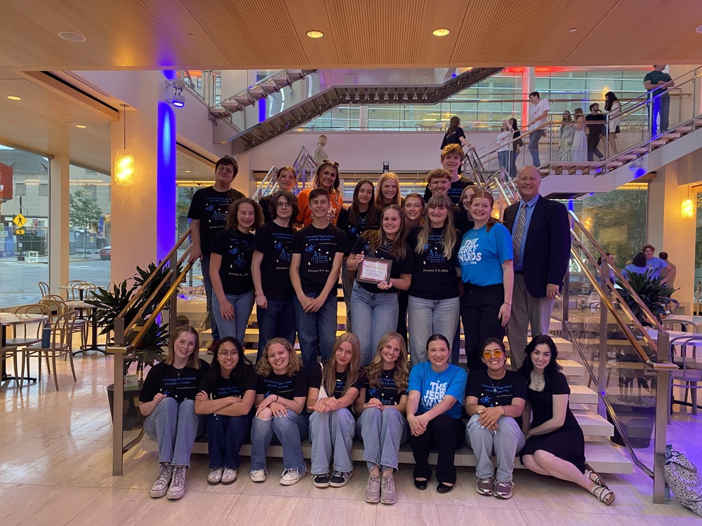 A group of students and adults posing on a staircase inside a modern building.