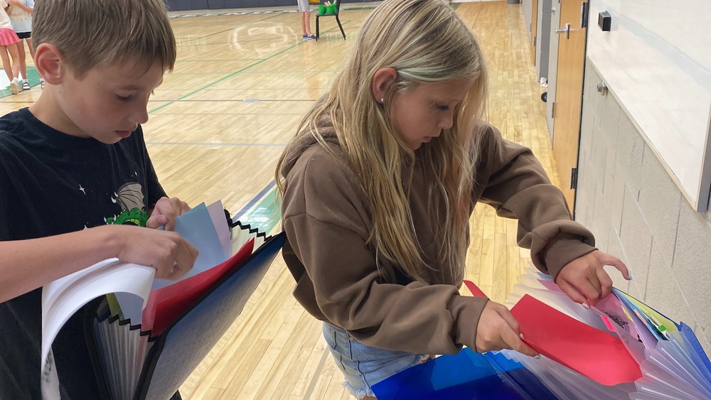 Students filling accordion folders with paper.