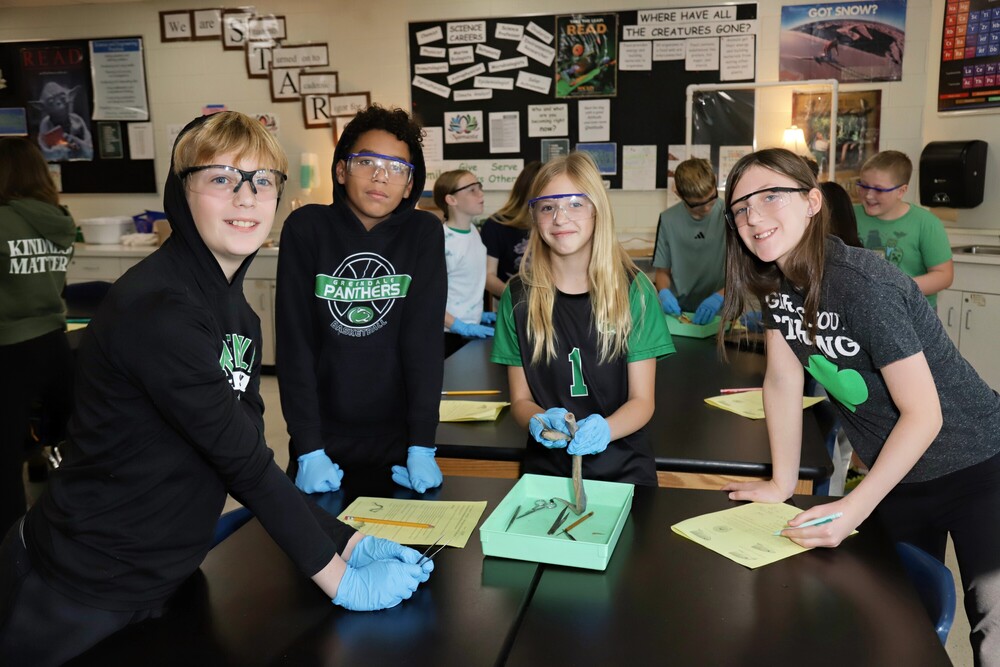 Four students conducting a science experiment looking at the camera