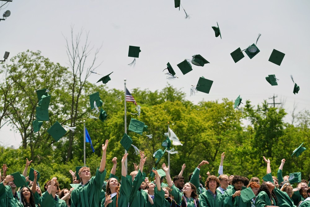 Graduates tossing caps outside.