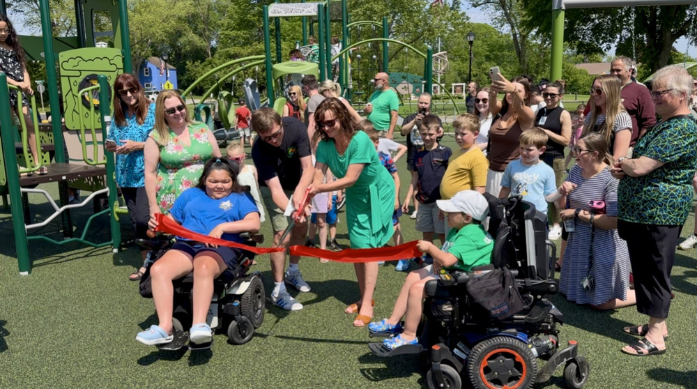 People standing and cheering at Jaycee Park when the ribbon was cut to open the playground.