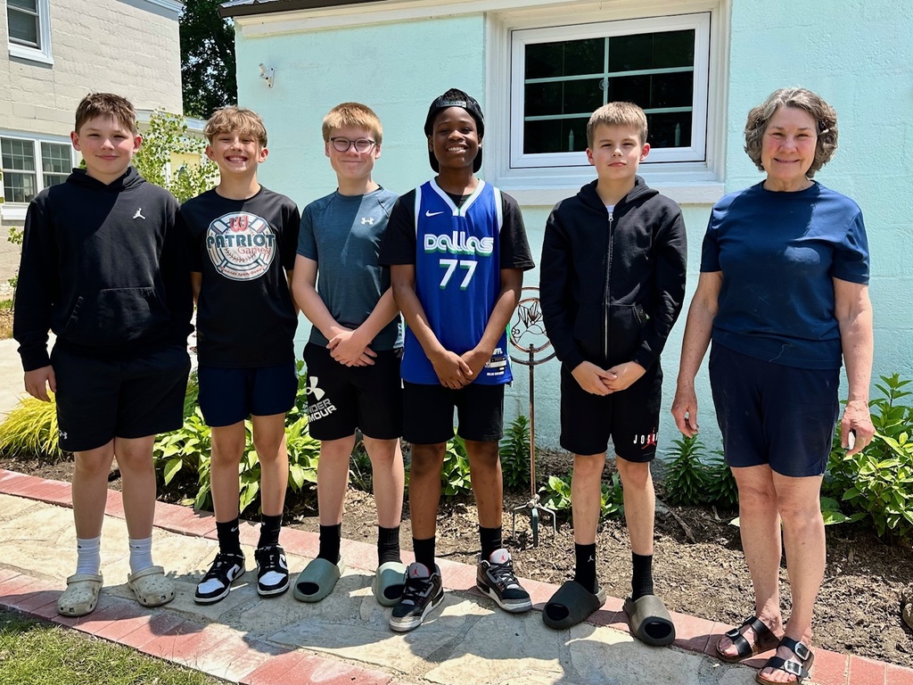 Five boys standing in front of a house with an elderly homeowner smiling.