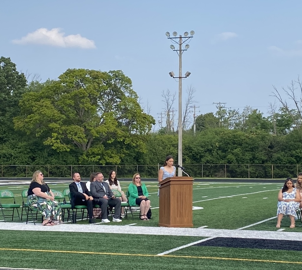 Student at podium with staff members watching.