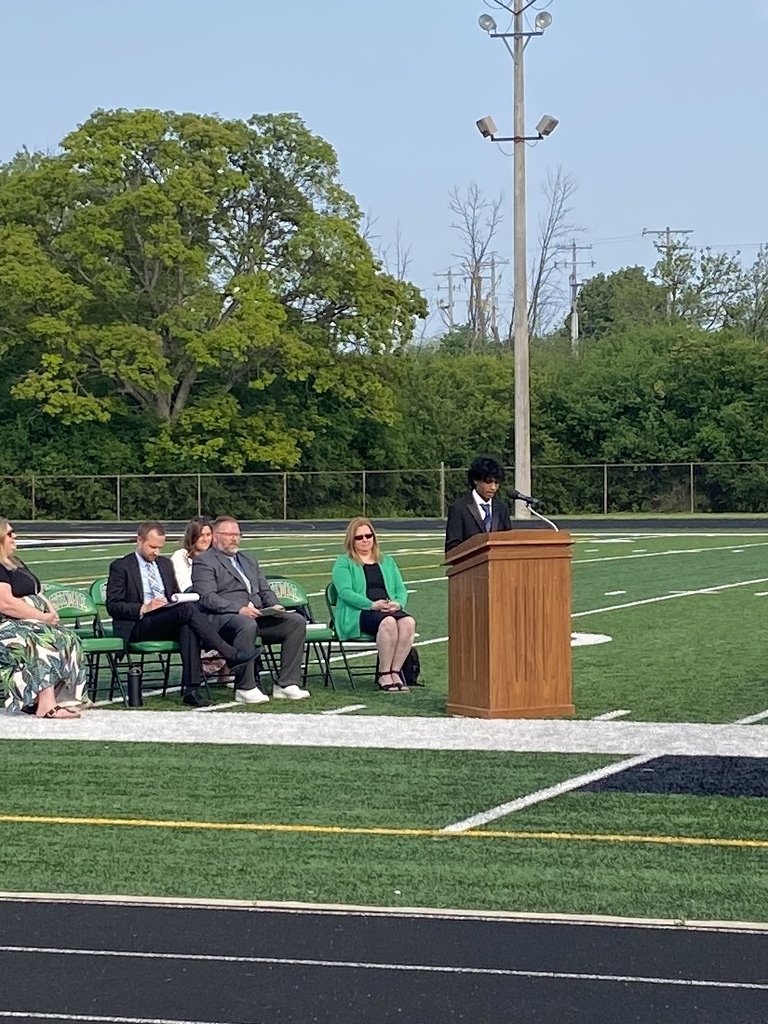 Student in a suit at podium with staff watching.