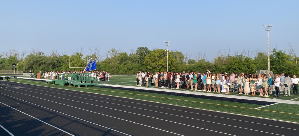 GMS Students standing in stadium. Flags on stage blowing.