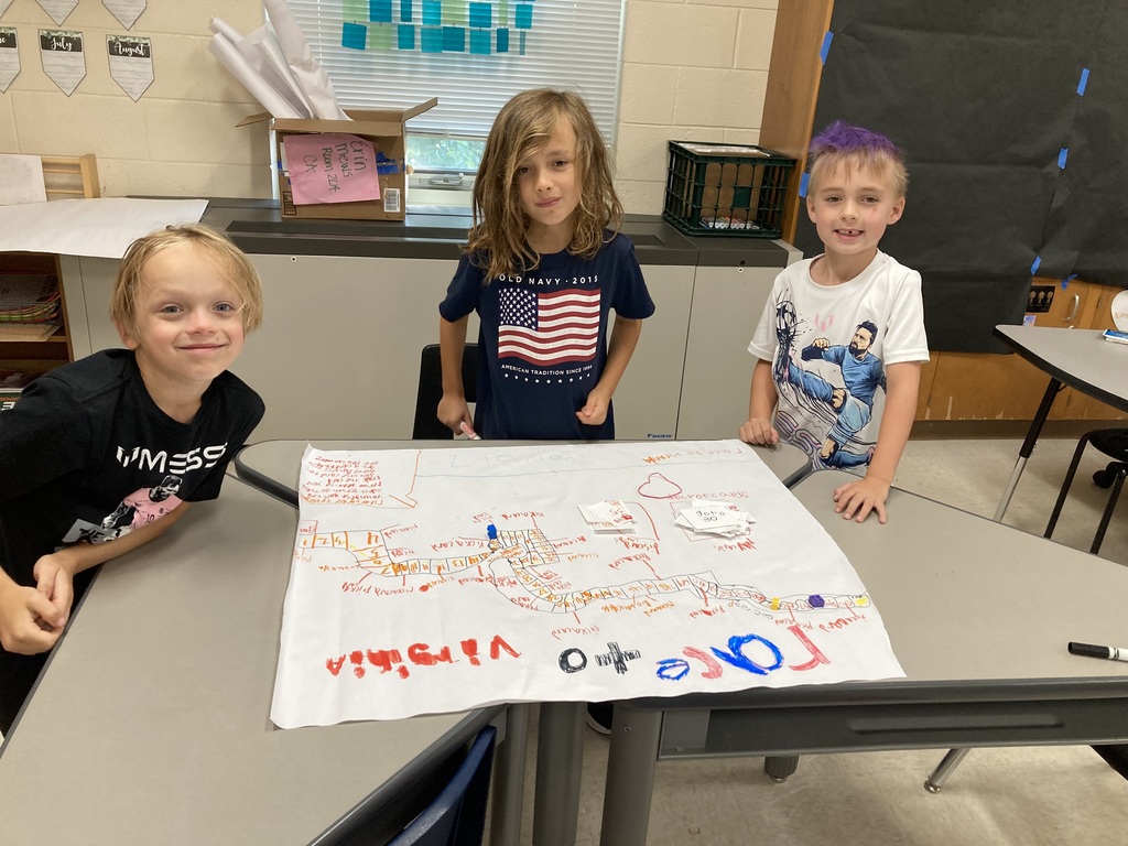 Three students smiling with their game board in front of them.
