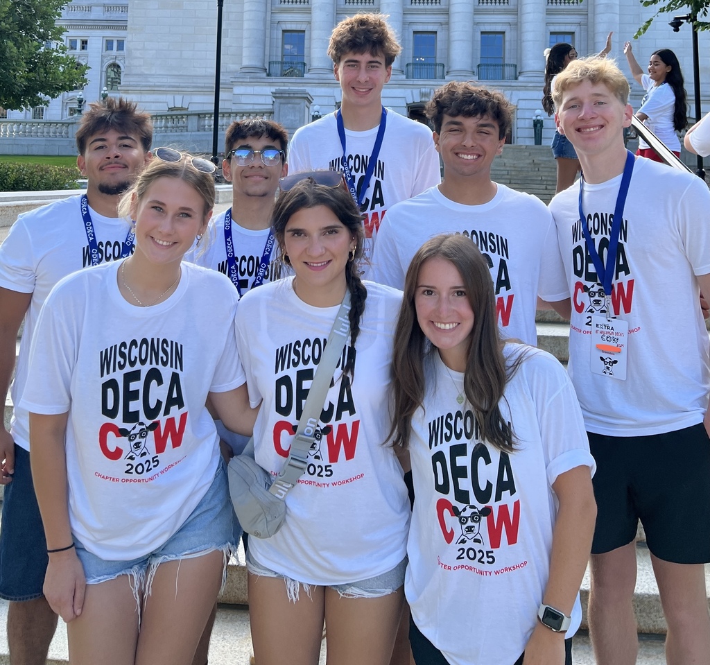 Eight students standing in front of the state capitol building smiling with matching shirts on.