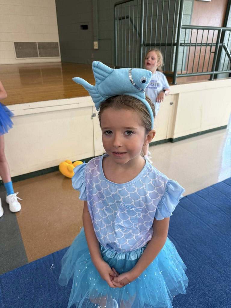 A little camper in blue wearing a fish hat