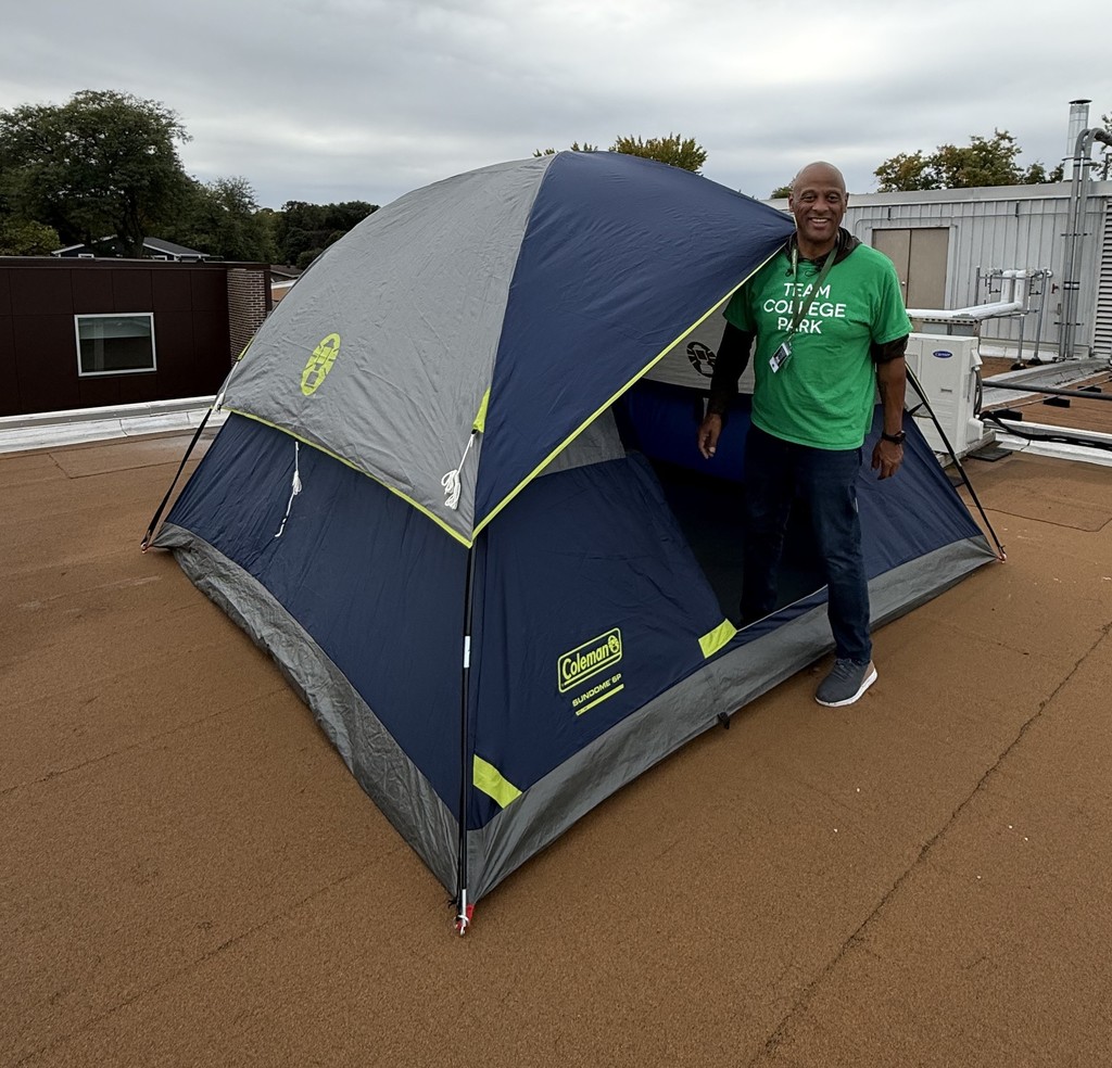 Mr. Brock, standing in the doorway of a tent, set up on the room of the school.