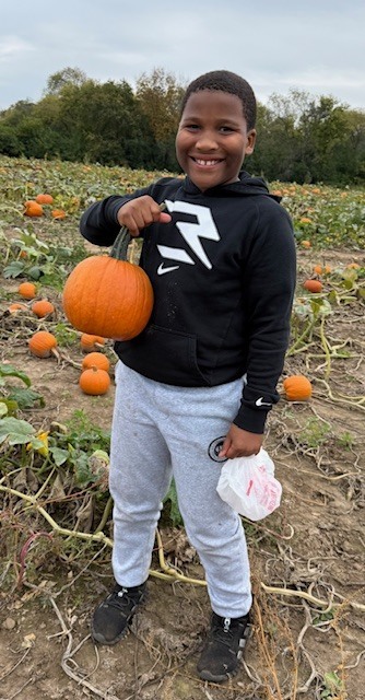 Student with pumpkin smiling at camera