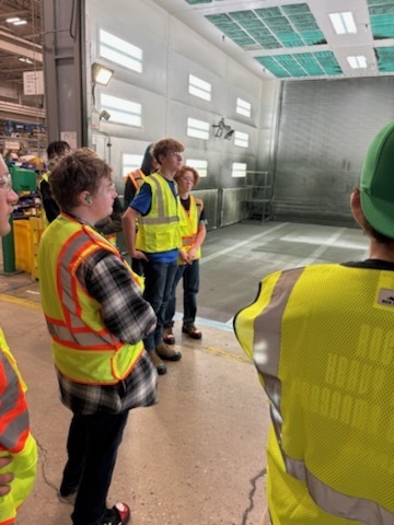 students in yellow vests looking at a demonstration