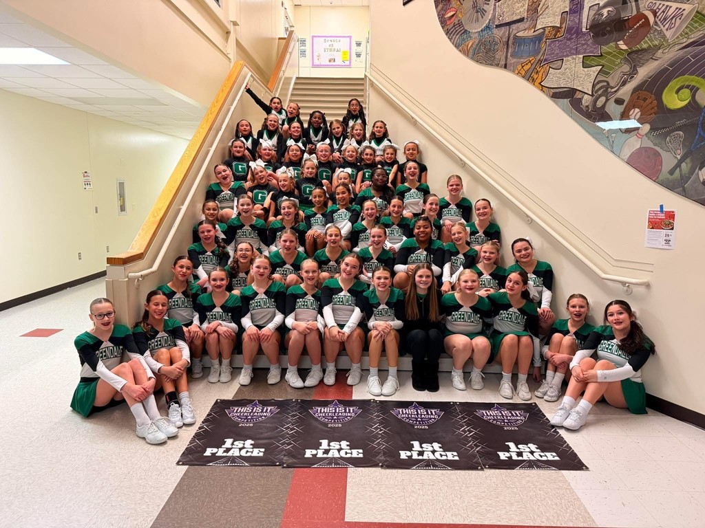 Cheerleaders sitting with banners after finishing in first place at a competition.