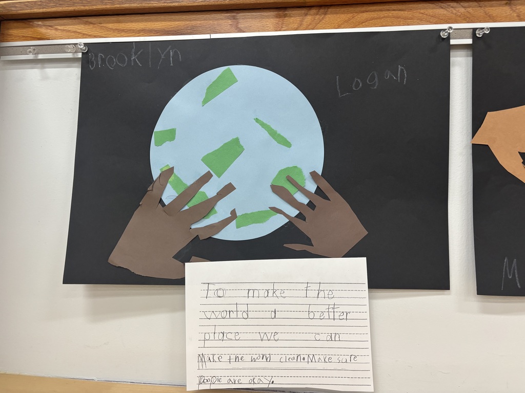 Students handprints touching a light blue globe posted on a black piece of paper and writing how to make the world better by making the world clean and making sure people are ok.