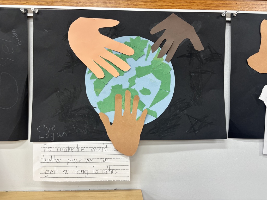 Students handprints touching a light blue globe posted on a black piece of paper and writing how to make the world better by getting along with others.