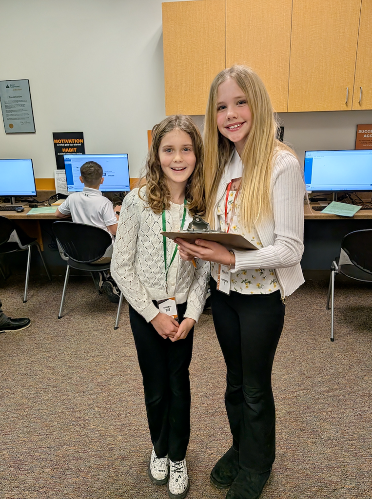 Two smiling girls working their "jobs" at BizTown simulation
