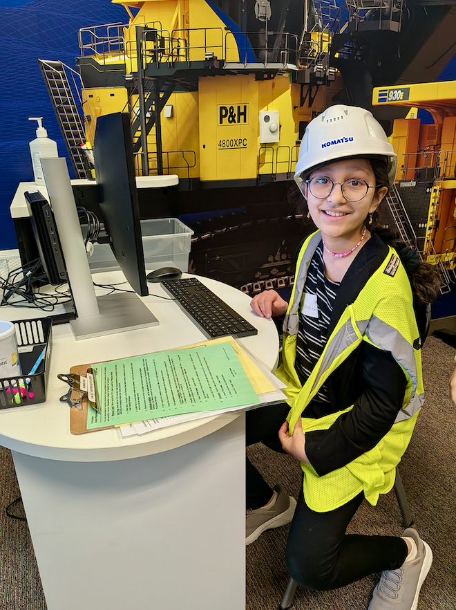 Girl in hard hat and safety vest working her "job" at BizTown simulation