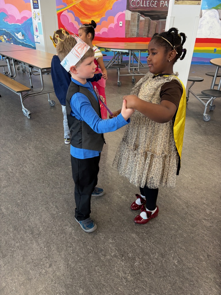 A boy and a girl dressed like royalty dancing hand-in-hand