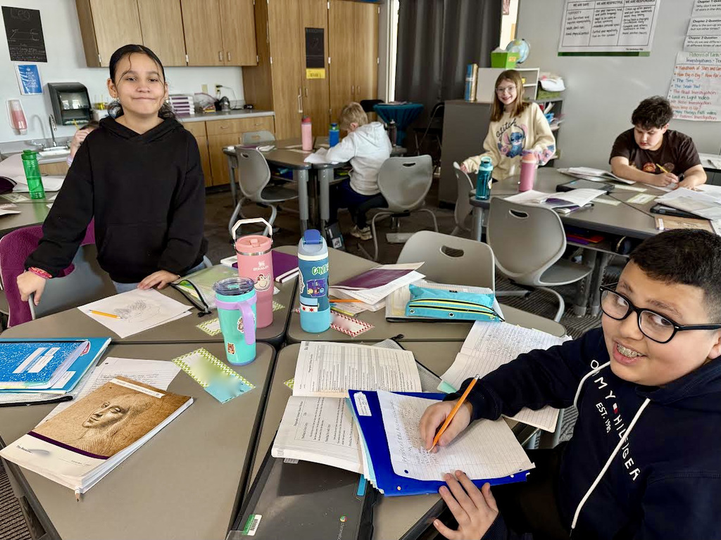 Fifth grade students working on ELA project at desks.