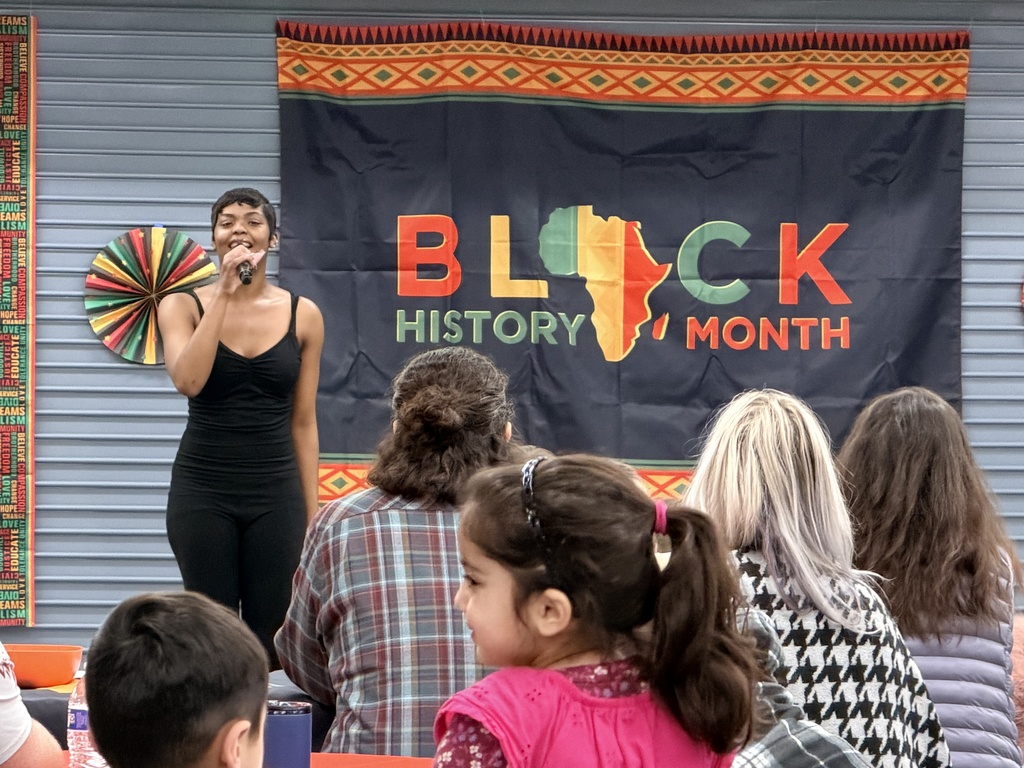 African American performer singing in front of a Black history month banner.