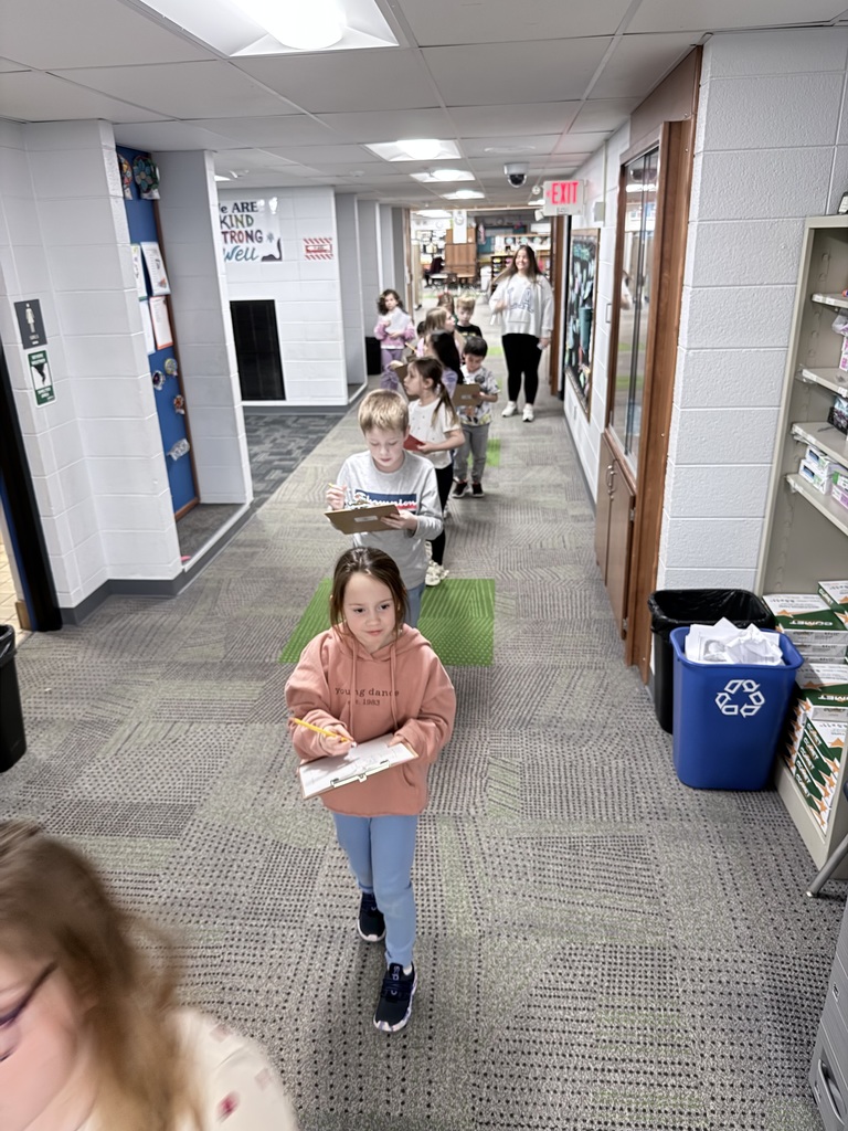 Curious 1st graders walking in a line in the hallway taking notes about light sources.