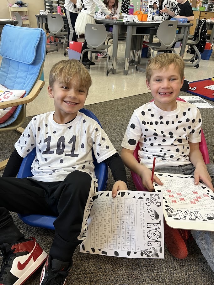 Two smiling boys in Dalmatian spirit wear working on assignments for 101 days of school celebration.
