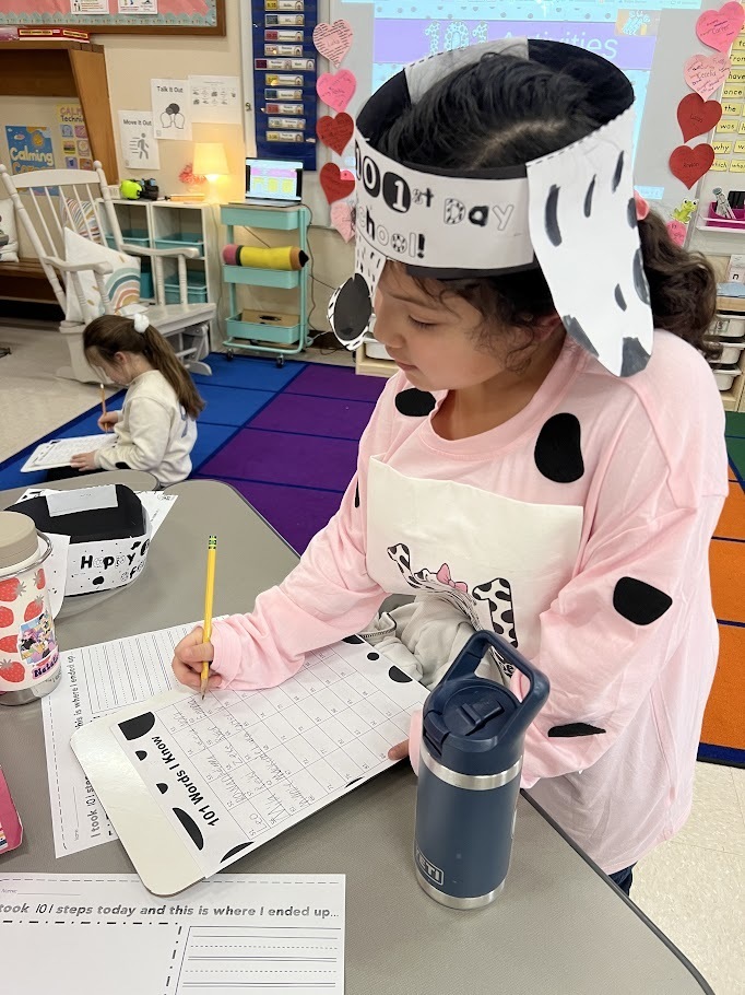 First grade girl working on an assignment celebrating 101 days of school in Dalmatian spirit wear.