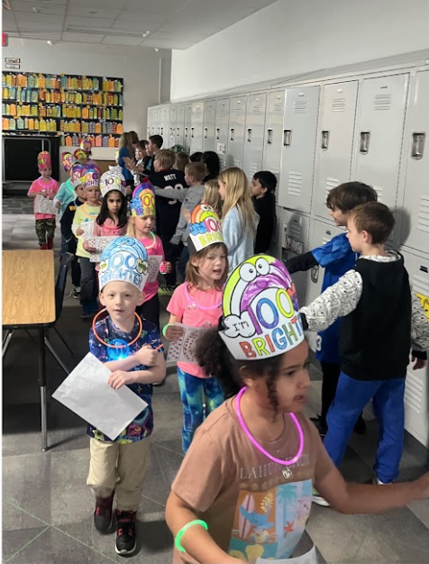 5K students in 100th day of school crowns parading in the school halls with cheers from other students.