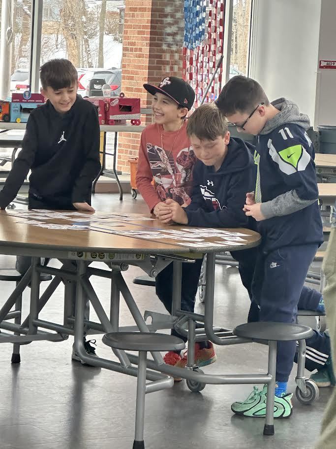 A four-boy team of Battle of the Books participants working together to come up with an answer.