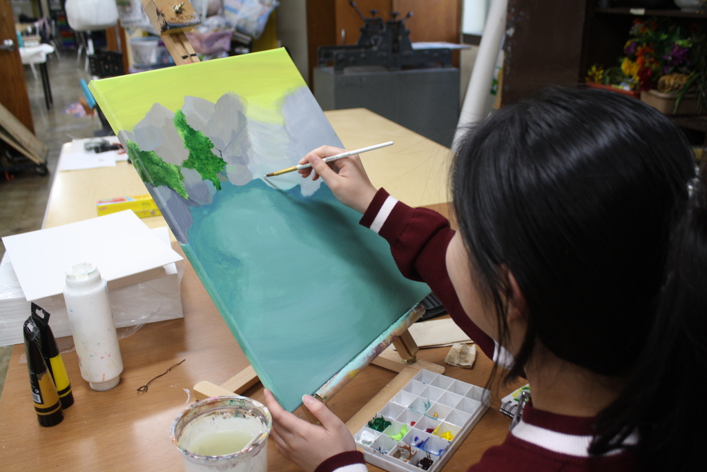 A person painting a landscape on a canvas in an art studio.