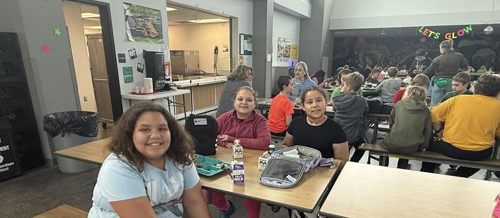 Group of girls at a lunch table smiling during the Glow reward lunch.