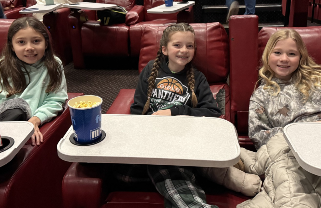 Three girls smiling at all-school movie field trip.